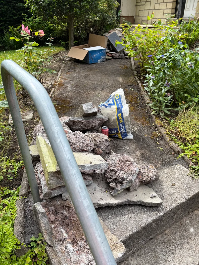 Bagged material and rubble awaiting collection on a garden path